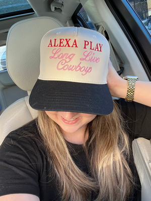 Woman wearing a trendy beige and black trucker hat from the set, featuring bold red embroidery with the text 'Alexa Play Long Live Cowgirls.' A stylish accessory perfect for casual outings and a must-have for hat enthusiasts.