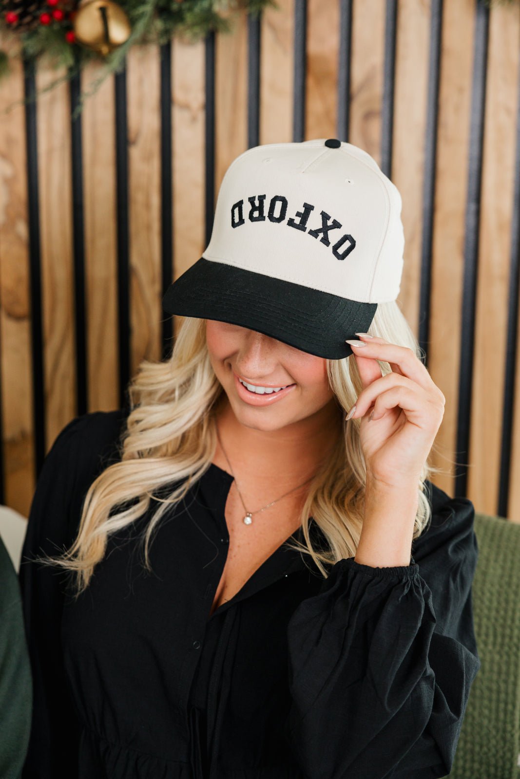 Image of two baseball caps, each featuring a different color scheme and text. The left cap has a cream crown with a navy blue bill and displays the word '75204' in navy thread, embroidered in a stylized font. The right cap has a cream crown with a dark green bill and shows the word 'NASHVILLE' in black thread, also in a stylized font. Both caps have a structured design with adjustable snaps at the back.