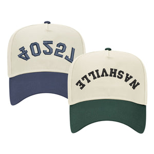 Image of two baseball caps, each featuring a different color scheme and text. The left cap has a cream crown with a navy blue bill and displays the word '75204' in navy thread, embroidered in a stylized font. The right cap has a cream crown with a dark green bill and shows the word 'NASHVILLE' in black thread, also in a stylized font. Both caps have a structured design with adjustable snaps at the back.