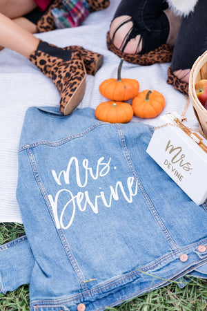 A jean jacket lays with a custom clutch showing the customized last name on the back