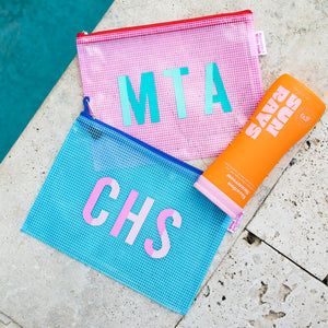 A blue and a pink pool bag are customized with colorful monograms at a pool