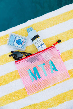 A pink pool bag is customized with a blue monogram and filled with pool essentials.