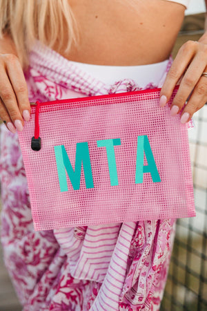 A girl holds up a pink pool bag with a two toned monogram.