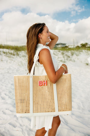 A girl at the beach holds a pink and orange monogrammed canning tote over her shoulder