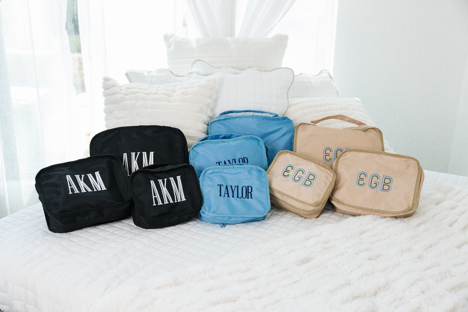 A set of three navy packing cubes are customized with a navy monogram.