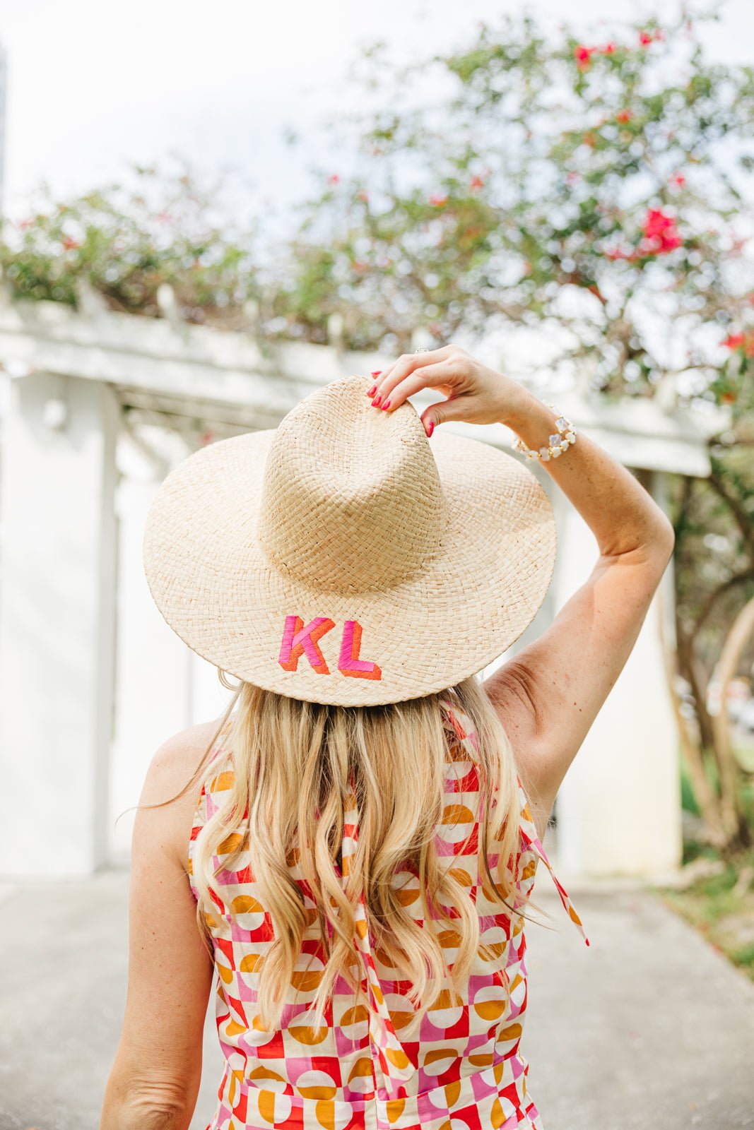A straw beach hat with "MC" embroidered on the brim