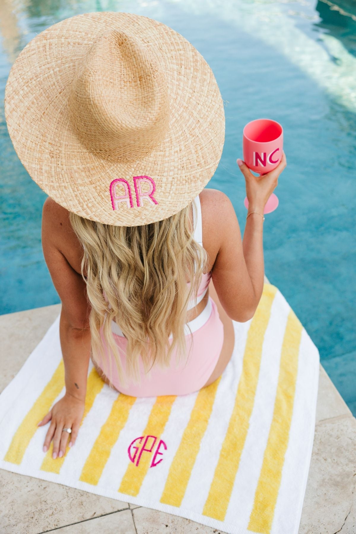 A straw beach hat with "MC" embroidered on the brim