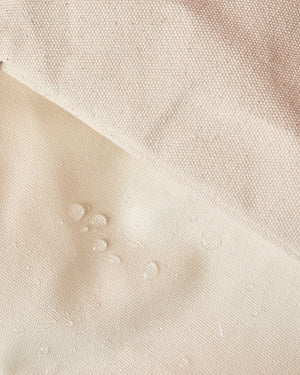 Water droplets sit on the surface of a coated canvas tote showing the water resistant material.