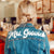 A woman shows off her custom retro denim jacket which reads "Mrs. Goswick" in white text across her shoulders.