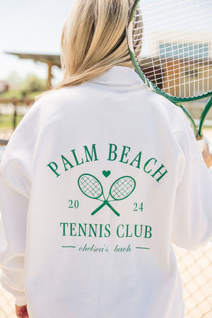 A girl in a white Last Swing Before The Ring sweatshirt holds up a green tennis racket