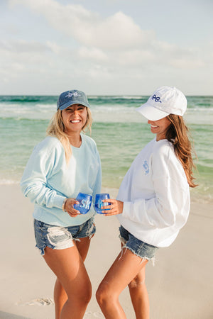 Two girls cheers with their monogrammed wine glasses wearing customized bachelorette apparel.