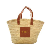 A straw tote is customized with a gold monogram.