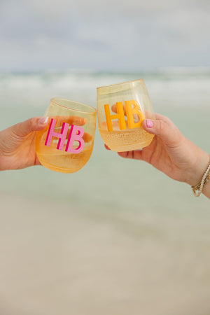 Two people on the beach cheers with their set of yellow wine glasses.