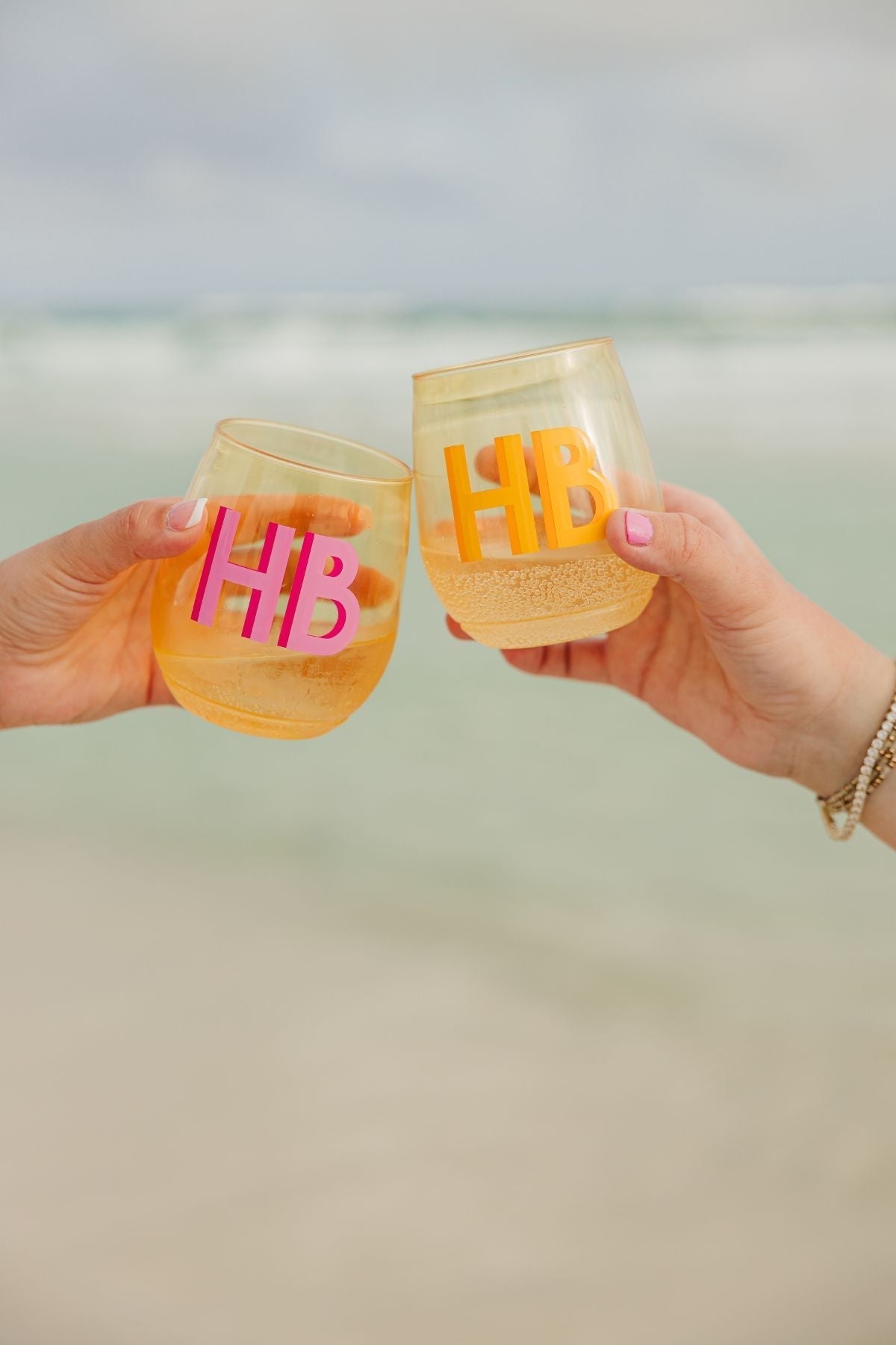 Two people cheers with their blue monogrammed wine glasses.