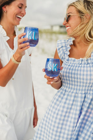 Two girls celebrate with two blue monogrammed wine glasses.