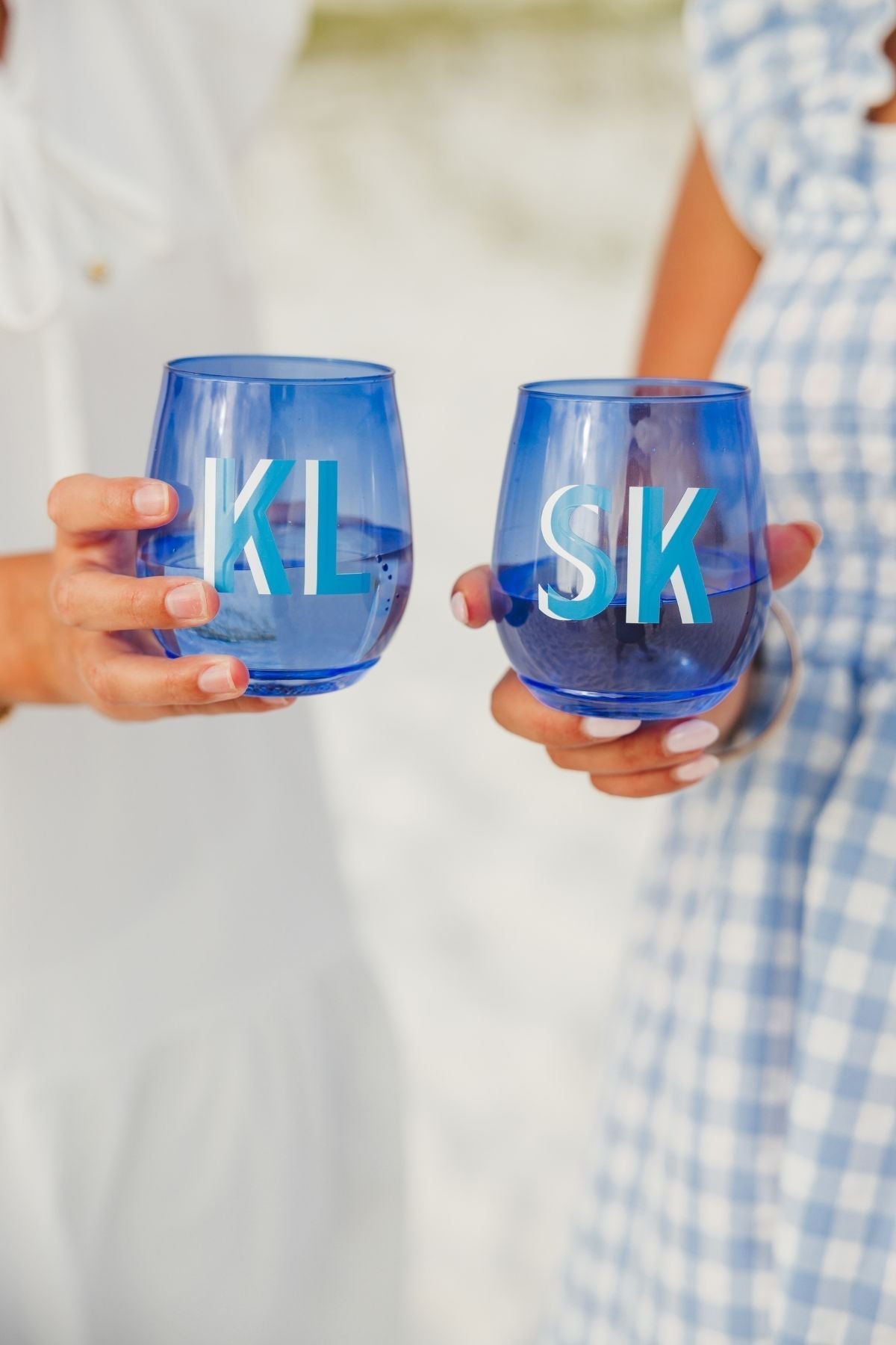 Two people cheers with their blue monogrammed wine glasses.