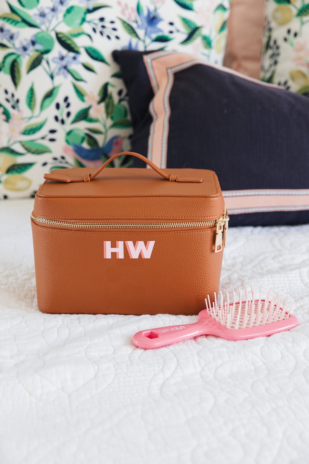 A group of white, tan, and black train cases are personalized with colorful monograms.