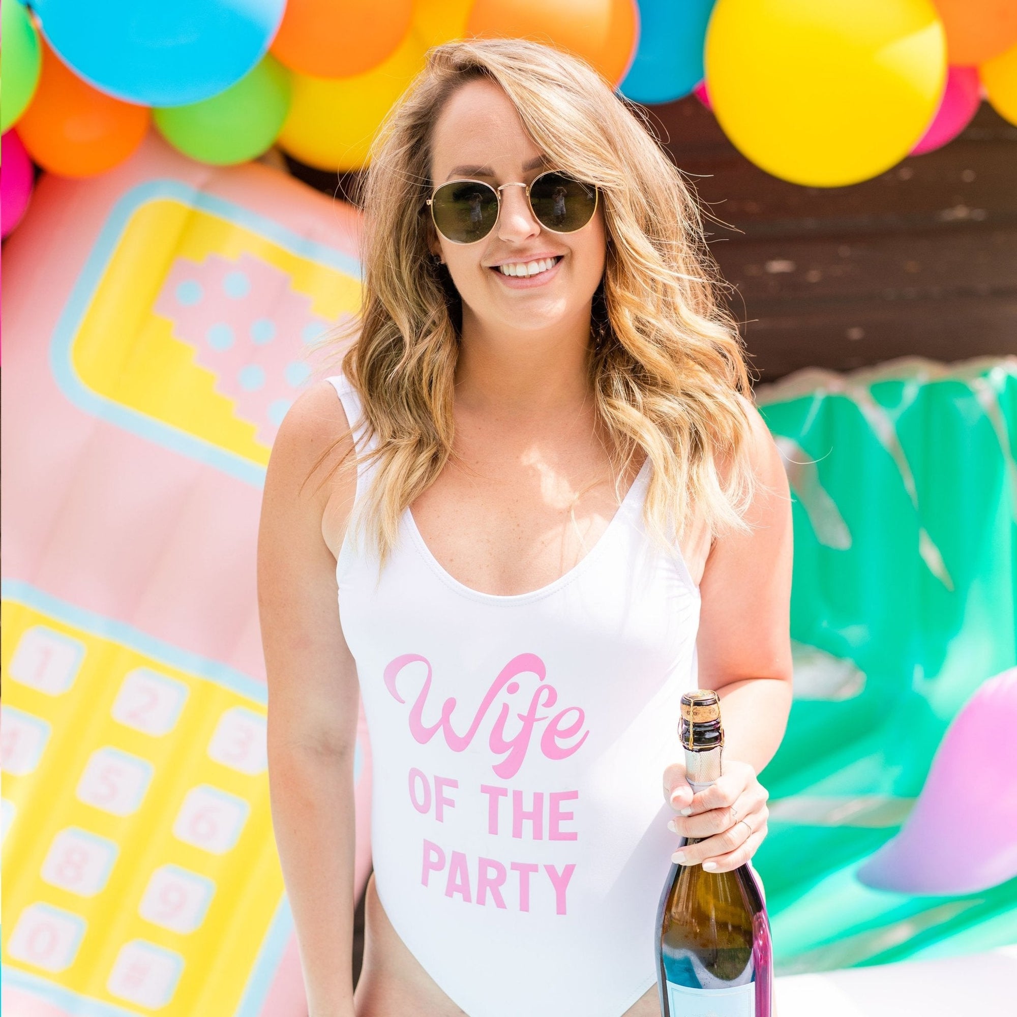 Two swimsuits one pink and one white read "Wife of the Party" and "The Party"