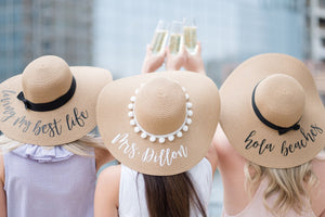 Three women cheers in their custom floppy beach hats with script font