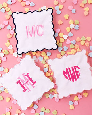 A few cocktail napkins with monograms are laid out with candy hearts