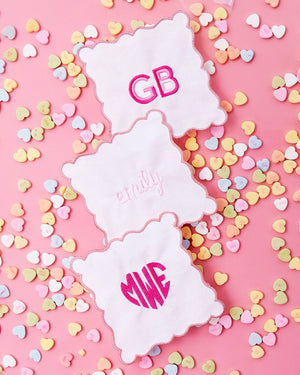 A few cocktail napkins with monograms are laid out with candy hearts