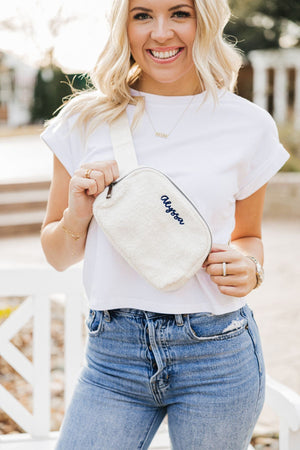 A woman shows off her sherpa belt bag customized with her name in a navy thread color.