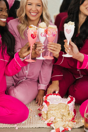 A group of girls cheers champagne flutes filled with cake to celebrate Valentine's