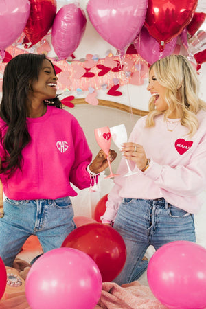 Two girls cheers champagne flutes with hearts to celebrate Valentine's