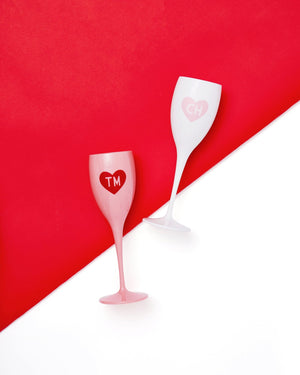 Two champagne flutes are monogrammed with a heart design