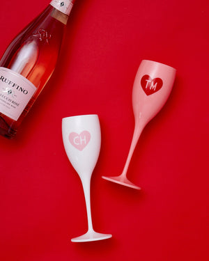 Monogrammed champagne flutes lay on a red background.