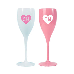 Pink and white champagne flutes are decorated with monogrammed heart designs.