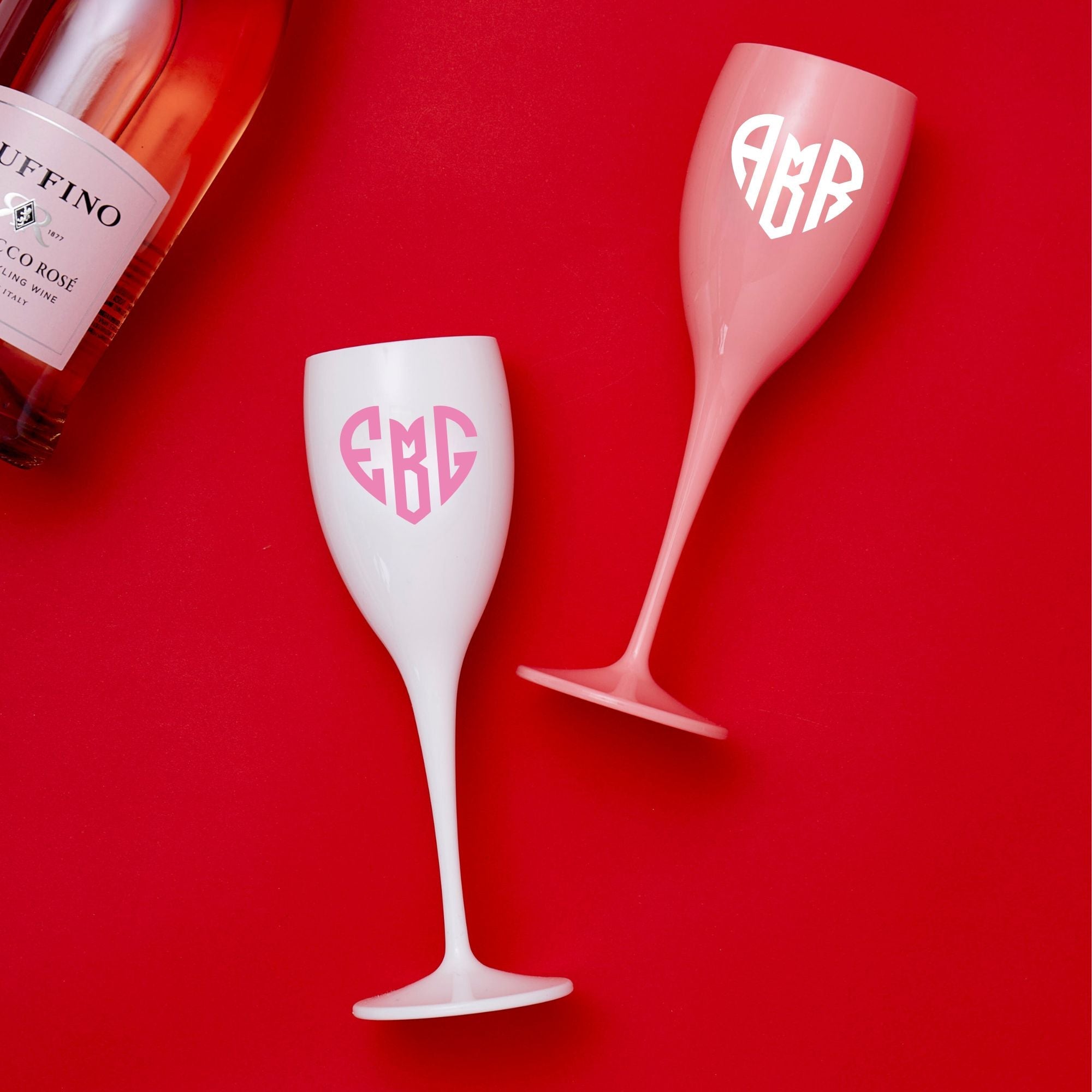 Pink and white champagne flutes are decorated with monogrammed heart designs.