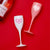 Pink and white champagne flutes are decorated with monogrammed heart designs.