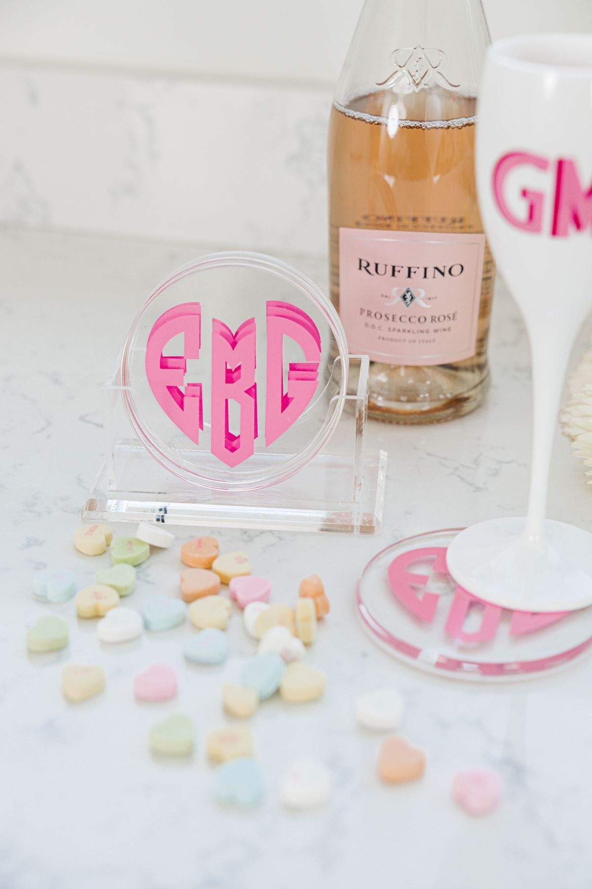 A set of coasters sits in a holder showing off it's custom red heart monogram.