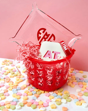 A basket with monogram gifts is put together for Valentine's Day