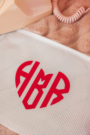 A white pouch featuring monogrammed heart design in red