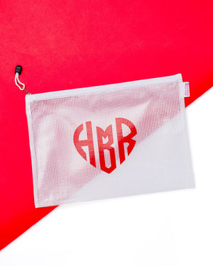 A white pouch featuring monogrammed heart design in red