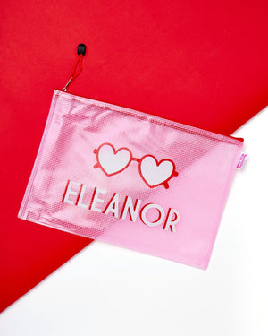 A pink pouch featuring heart sunglasses and customized with a name.