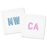 Two monogrammed cocktail napkins are laid out on a white background to show off some of the customization options.