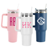 Three monogrammed tumblers with handles in pink, white, and blue