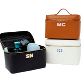 A group of white, tan, and black train cases are personalized with colorful monograms.